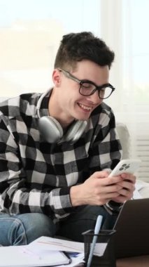 Uykulu erkek, beyaz, genç, uzaktan kumandalı işçi. Çalışırken yorgunluk çekiyor, evde gözlerini ovuşturuyor. Dikey video.