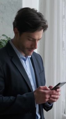 Düşünceli Kafkas erkek çalışanı internette sohbet etmek ve internette internette gezinmek için cep telefonu kullanıyor. Kullanılan bir cihaz kavramı. Dikey video.
