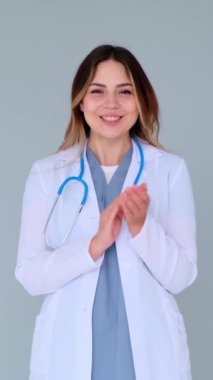 Tebrik etmek ya da mavi arka planda kabul görmek için gülümseyen genç, yetişkin kadın, beyaz profesyonel alkış. Kutlama ve anlaşma kavramı. Dikey video.