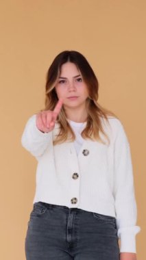 Reddedilmiş ya da reddedilmiş, bej arka planda duran beyaz bir kadının portresi. Sevmediğine dair işaret. Dikey video.