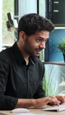 Mutsuz, genç, yetişkin bir erkek çalışanın facepalm jesti göstermesi ofiste çalışırken yaşadığı sorun ya da hatadan rahatsız olması. Dikey video.