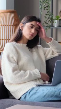 Düşünceli kadın, beyaz, genç, serbest çalışan, evde dizüstü bilgisayarla çalışan ve düşünen. Finansal iş planlamasıyla meşgul. Dikey video.