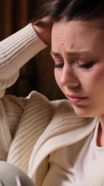 Kızgın, beyaz, kederli genç bir kadın. Ağlıyor, gece yarısı evde oturuyor. Hayal kırıklığı ve depresyon kavramı. Dikey video.