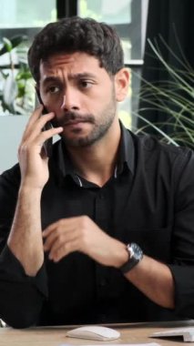 Ciddi bir Ortadoğulu işadamı telefonda konuşuyor ya da müşteriyle görüşüyor. Ofiste çalışıyor. Dikey video.