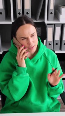 Güler yüzlü kadın, beyaz tenli orta yaşlı çalışan. Tatil sırasında arkadaşlarıyla telefonda konuşuyor. Çağrı ve iletişim kavramı. Dikey video.