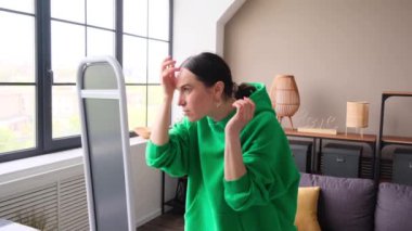 Kafkasyalı mutlu orta yaşlı kadın saç stili düzenliyor ve evde aynaya bakıyor. Sabah güzellik anlayışı ve hazırlık..