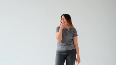 Tembel ve sıkılmış Kafkasyalı genç kadın esniyor, beyaz arka planda tek başına duruyor. Yorgunluk, melankoli, yorgunluk, yorgunluk konsepti.