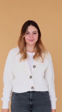 Heyecanlı genç beyaz kadın bej arka planda onay ya da onay işareti gösteriyor. Anlaşma ve mükemmellik kavramı. Dikey video.