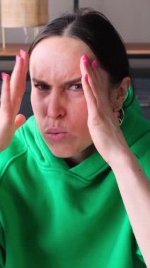 Evinde korkmuş ve korkmuş orta yaşlı beyaz bir kadının portresi. Korku, sürpriz ve kafa karışıklığı kavramı. Dikey video.