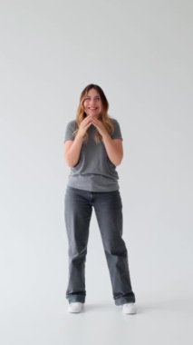 Dost canlısı bir kadın başarıyı kutluyor ve beyaz arka planda el çırpıyor. Takdir, zafer ve dostça bir kavram. Dikey video.