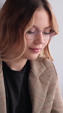 Ofiste, çekici ve mutlu genç bir beyaz kadın portresi var. Neşeli bir yönetici ya da iş adamı kavramı. Dikey video.