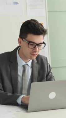 Ofiste dizüstü bilgisayarı ve planlama bütçesi ile çalışan profesyonel Kafkasyalı genç iş adamı ya da teftiş ifadeleri. Dikey video.