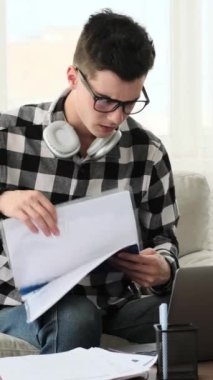 Yorgun, Kafkasyalı genç bir adam evden çalışırken esniyor ve esniyor. Yorgunluk ve fazla mesai kavramı. Dikey video.