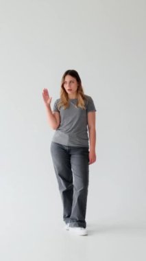 Beyaz arka planda garip hareketler yapan Kafkasyalı genç bir kadın. Sohbet kavramı, dedikodu ve sohbet. Dikey video.