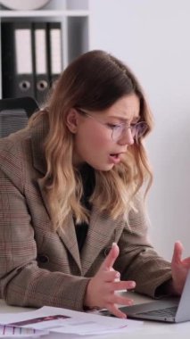 Ofiste dizüstü bilgisayarla çalışırken yapılan hatalara şaşıran depresyondaki genç beyaz kadın çalışan. Çarpışma ve zorluklar kavramı. Dikey video.