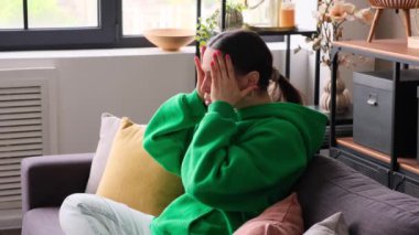 Hayal kırıklığına uğramış ve yorgun Kafkasyalı genç bir kadın baş ağrısı çekiyor. Oturma odasındaki kanepede oturuyor. Sağlık sorunları var. Acı, üzüntü, yorgunluk konsepti..