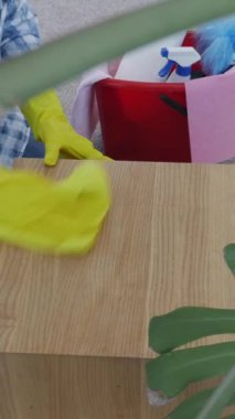Bir kadının eldiven giyip, temizlik sırasında evde bez kullanarak mobilyaların tozunu alırken yakın plan fotoğrafını çek. Ev ödevi rutini konsepti. Dikey video.