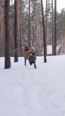 Güler yüzlü, orta yaşlı erkek arkadaş ve kız arkadaş kış mevsiminde ormanda kartopu oynuyorlar. Emeklilik ve eğlence kavramı. Dikey video.