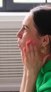 Kafkasyalı orta yaşlı, inançsız bir kadın televizyon seyrediyor ve haykırıyor, evde iyi haberleri kutluyor. Dikey video.