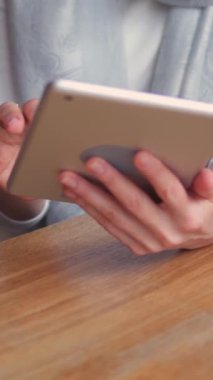 Konsantre olmuş Kafkasyalı kadın çevrimiçi boş zamanlarında meşgul ya da kafede tablet bilgisayarla çalışıyor. İnternet aktivitesi kavramı. Dikey video.