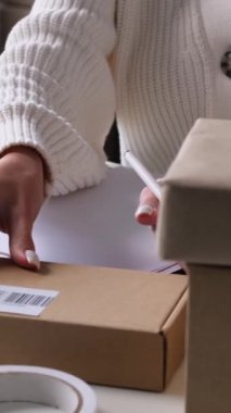 Çevrimiçi bir mağazada çalışan ve tablete yazı yazan bir kadının yakın plan fotoğrafı. Ticari mal dağıtımı ve lojistik konsept. Dikey video.