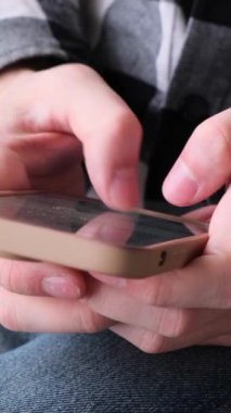 Evdeki cep telefonuyla internetten mesajlaşan ya da sohbet eden bir adamı yakından çek. Dijital eğlence ya da eğlence. Dikey video.