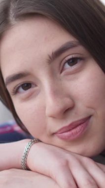 Dost canlısı ve olumlu bir genç beyaz kadının portresi gülümseyen ve kameraya bakan. Memnuniyet konsepti. Dikey video.