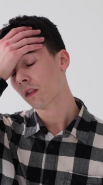 Üzgün ve üzgün genç, beyaz arka planda duran beyaz tenli bir adam. Utanç, başarısızlık ve hata kavramı. Dikey video.