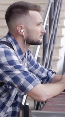 Kafkasyalı orta yaşlı bir adam kahve içiyor ve online eğlence için akıllı telefon kullanıyor. Siber uzayda boş zaman kavramı. Dikey video.