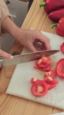 Mutfakta salata için domates kesen orta yaşlı beyaz bir kadının yakın çekimi. Sağlıklı ve taze yemek pişirme konsepti. Dikey video.