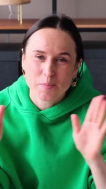 Gülümseyen orta yaşlı beyaz kadın blogcu evde kamerayla konuşuyor. Sosyal medya faaliyetleri ve iletişim kavramı. Dikey video.