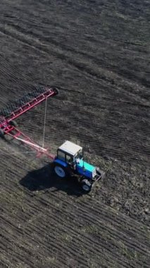 Bir traktörün toprağı sürdüğü kırsal alanın havadan görüntüsü. Tarımsal faaliyetler, güzel bir tarım arazisinde tarım. Dikey video.
