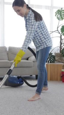 Evdeki yerleri süpürmek için süpürge kullanan heyecanlı orta yaşlı beyaz kadın. Günlük ev ödevi konsepti. Dikey video.