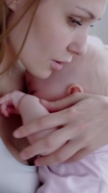 Beyaz, genç, yetişkin bir annenin evde ağlayan yeni doğmuş bir bebeği teselli etmesini seviyorum. Annelik ve bakım kavramı. Dikey video.