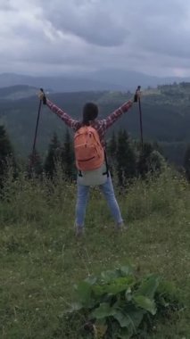 Neşeli bir kadın dağ yürüyüşünden zevk alıyor. Havadan çekilen nefes kesici doğal manzaralarla çevrili. Doğada keşif ve macera. Dikey video.