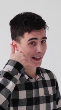 Beyaz arka planda bana işaret gösteren ve flört eden Kafkasyalı genç bir adam. İletişim ve sohbet konsepti. Dikey video.