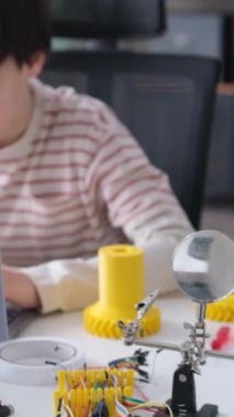 Evde bilgisayar ve 3D yazıcı kullanan beyaz bir çocuk e-öğrenme sürecine girdi. Mekanik proje araştırması yapıyor, prototip tasarlıyor ve modelliyor.