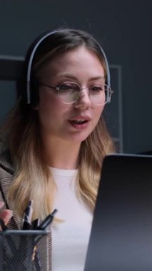 Ofiste çalışırken internet üzerinden müşteriyle uzaktan görüşme yapan gülen beyaz kadın çalışanı. Dikey video.