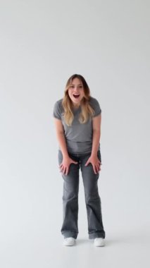 Şokta olan beyaz bir kadın beyaz arka planda haykırıyor. Merak, başarı ve başarı kavramı. Dikey video.