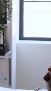 Ofiste yapılan toplantıda çok ırklı ciddi iş arkadaşları birlikte çalışıyor. Profesyonel iş ortaklığı kavramı. Dikey video.