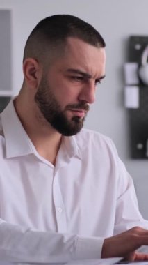 Kafkasyalı orta yaşlı işadamı ofiste dizüstü bilgisayarla çalışırken başarıyı kutluyor. İş ve memnuniyet kavramı. Dikey video.