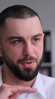 Ofisteki akıllı telefondan görüntülü arama yapan orta yaşlı, konsantre bir beyaz erkek çalışanın portresi. Çevrimiçi konuşma ya da konferans konsepti. Dikey video.