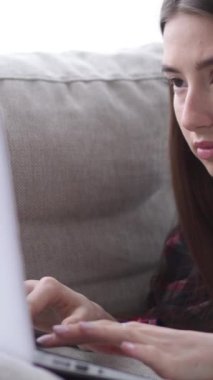 Konsantre olmuş Kafkas genç kadın evde dizüstü bilgisayarla çevrimiçi iletişim kuruyor. İnternet teknolojisi kavramı. Dikey video.