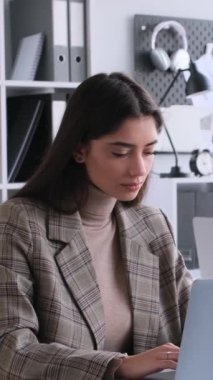 Ofiste çalışırken dizüstü bilgisayarla proje ve strateji planlayan Kafkasyalı genç kadın çalışanlar. Dikey video.