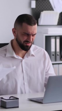 Kafası karışmış orta yaşlı iş adamı ofiste çalışırken kollarını açıyor. Sorunlar ve sorunlar kavramı. Dikey video.