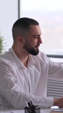 Kafkasyalı mutlu erkek, orta yaşlı çalışan ofiste çalışırken koltukta dinleniyor. Rahatlama, rahatlama ve sükunet kavramı. Dikey video.