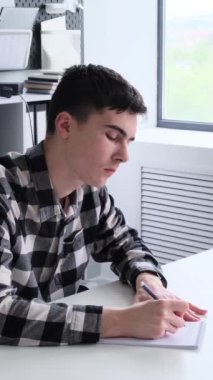 Ofisteki masada çalışan ve not defterine notlar alan Kafkasyalı genç bir işadamı. Düşünceleri ve fikirleri kaydediyor. Dikey video.