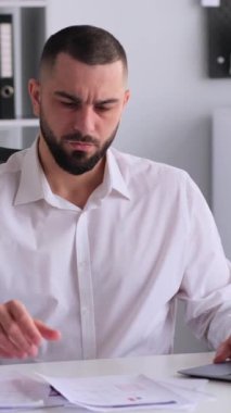 Neşeli Kafkasyalı orta yaşlı bir adam iş stratejisi geliştiriyor ya da modern ofiste çalışırken bütçeyi analiz ediyor. Dikey video.