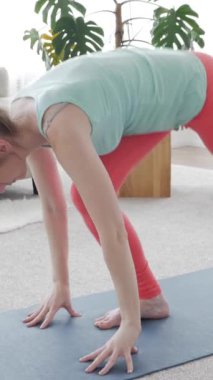 Huzurlu orta yaşlı beyaz kadın yoga eğitimi sırasında evde nefes alıp esneme egzersizi yapıyor. Eğlence konsepti. Dikey video.