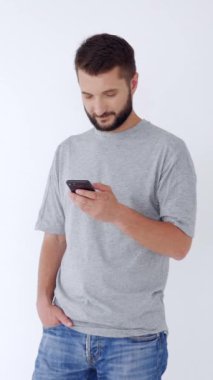 Neşeli orta yaşlı, beyaz arka planda cep telefonu kullanarak sosyal medyada sohbet eden beyaz bir adam. İnternet eğlence zamanı konsepti. Dikey video.